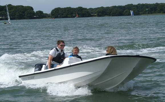 Three people riding in a speed boat on the water.